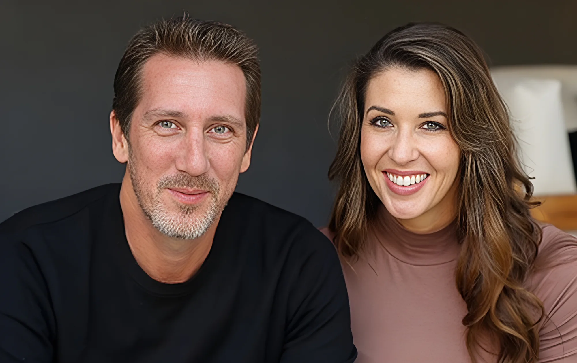 Chad and Lauren Munsey, the owners of The Huguenot, seated side by side against a dark grey wall.