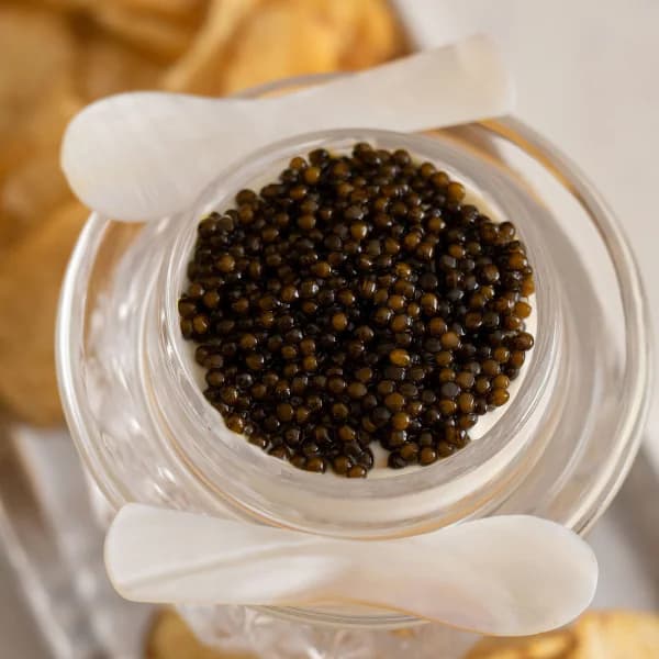 Caviar in a cut-crystal jar with mother-of-pearl spoons, on a tray of kettle chips.